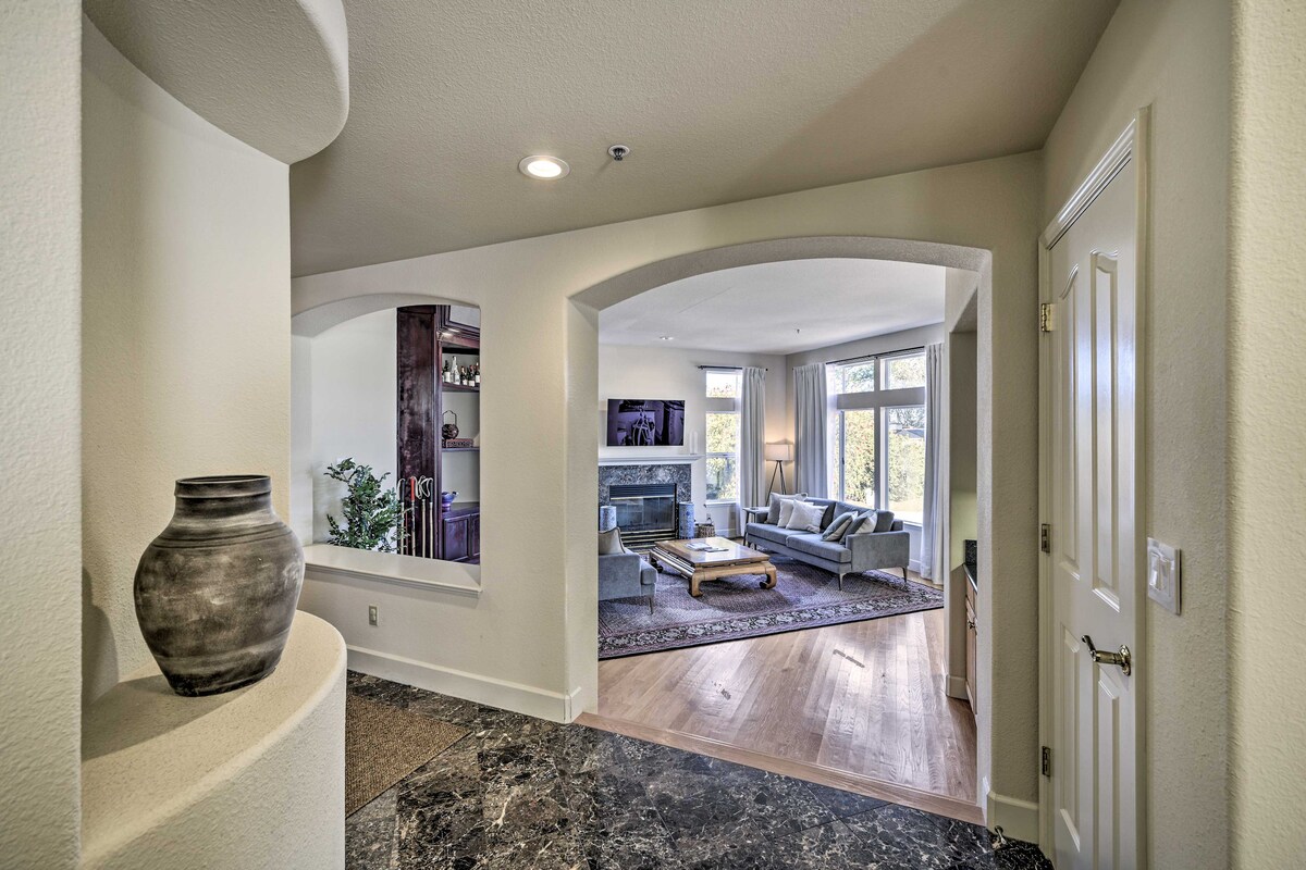 A spacious entryway leads into a living area featuring large windows that allow natural light to fill the room. A comfortable seating arrangement is visible, with a coffee table at its center. A decorative vase is positioned on the entryway table, contributing to the welcoming ambiance.