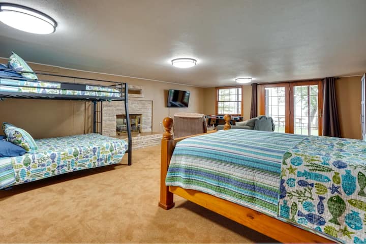 Plocha suterénu s manželskou posteľou a manželskou posteľou. TV, Pac-Man Arcade a Air hockey v juhovýchodnom rohu