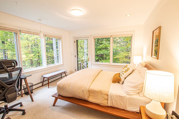 Chumba cha 2 cha kulala kina dawati lenye skrini/kibodi/panya, kiti cha starehe na mlango unaoelekea nje.