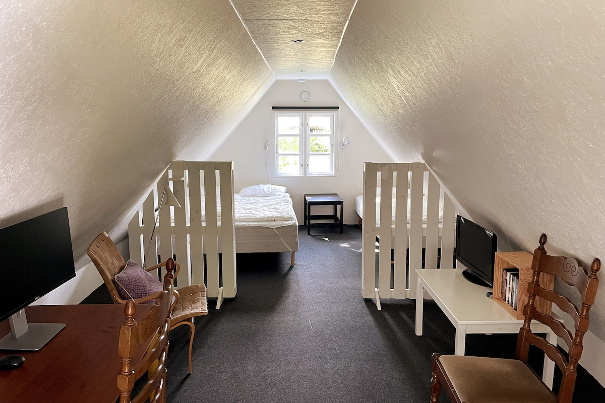 Bijlage (1e verdieping) met tweepersoonsbed en eenpersoonsbed, evenals werkruimte met scherm, printer, enz. 