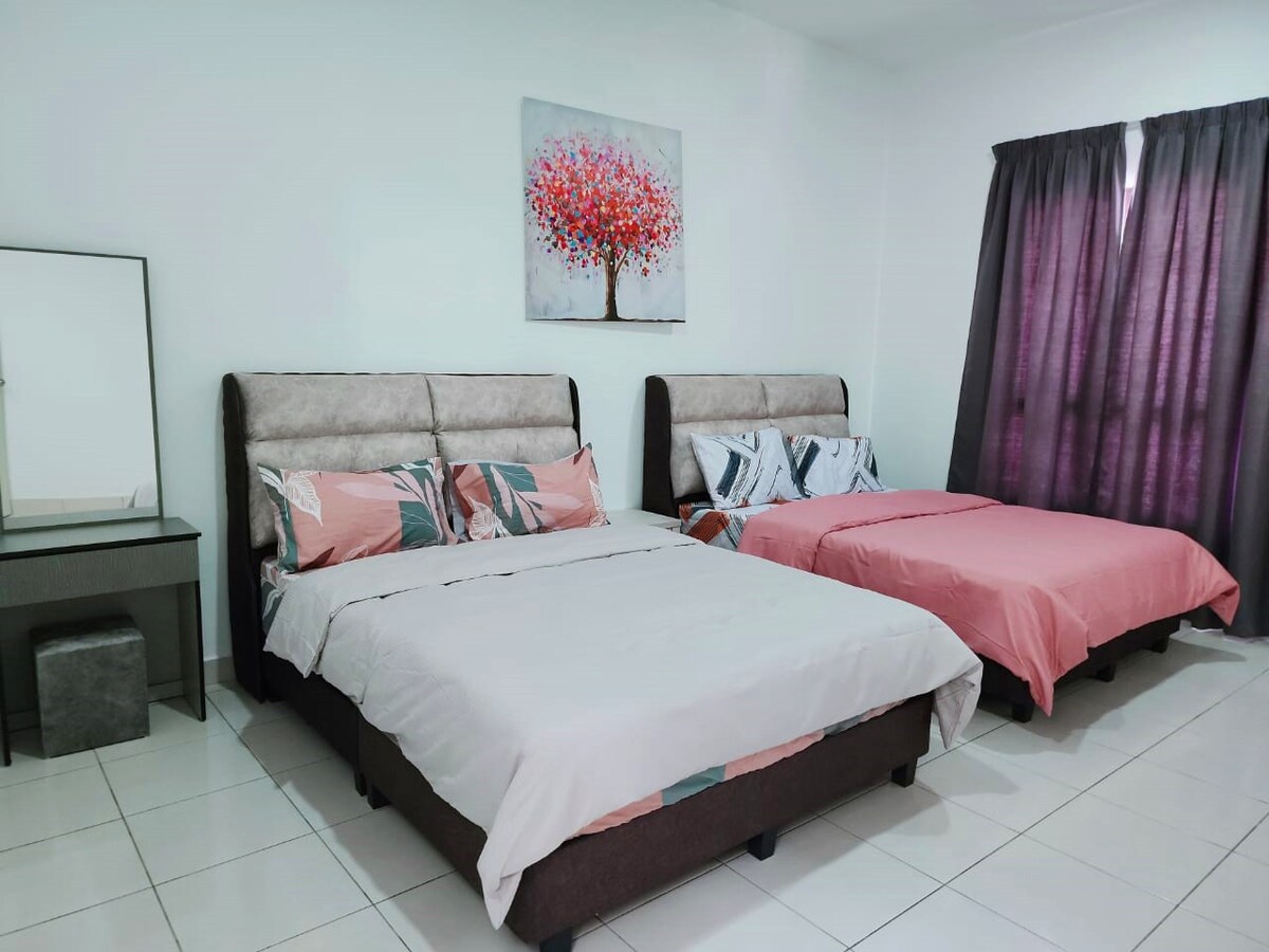 The bedroom features two spacious beds adorned with soft linens in complementary colors. A large mirror reflects the room's layout, and a vibrant wall art piece adds a touch of color. Huge windows are draped with dark curtains, allowing for light control.