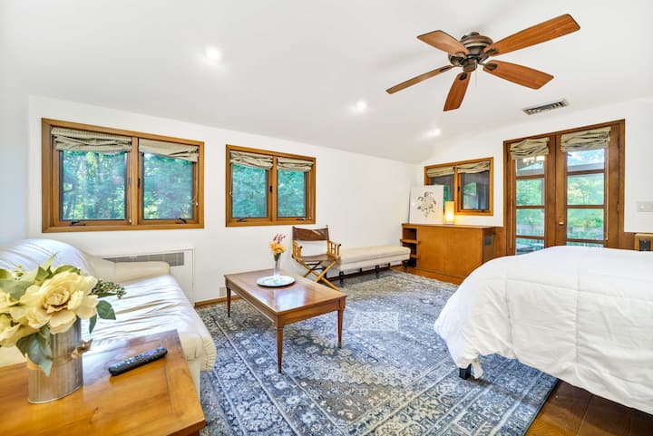 The master bedroom has a king bed, a leather sofa that pulls out to a slatted memory foam full bed, and a private screened room that overlooks the woods on the north side of the house.