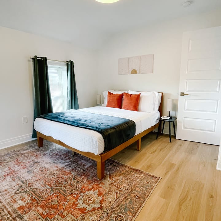 Chumba cha kulala chenye mwanga, kinachovutia chenye kitanda cha ukubwa wa kawaida, mito ya kupendeza na vipengele vya kisasa—kinatoa sehemu ya kustarehesha, yenye utulivu iliyojaa mwanga wa asili na muundo rahisi, wa kimaridadi.