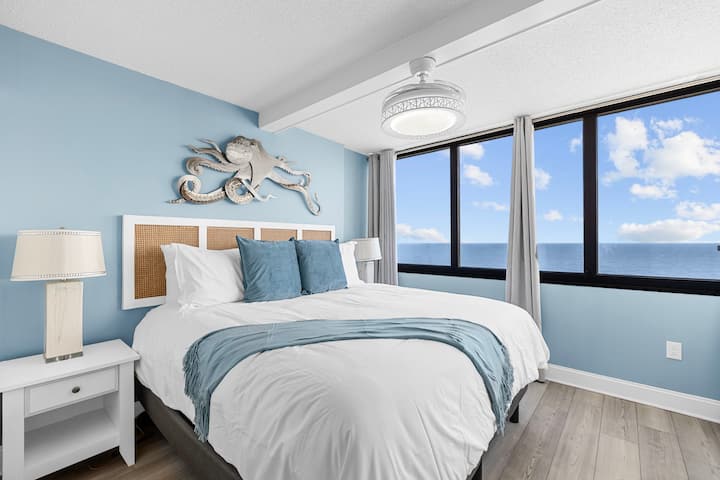 King-sized bed and coastal decor in the Primary bedroom with amazing views! 