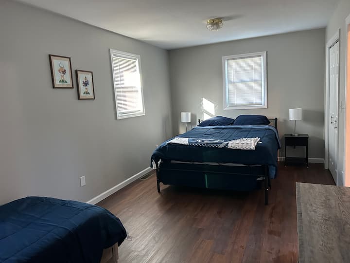 غرفة نوم رئيسية بسرير بحجم كوين وسرير مزدوج وخزانة ملابس وتلفزيون وخزانتين.