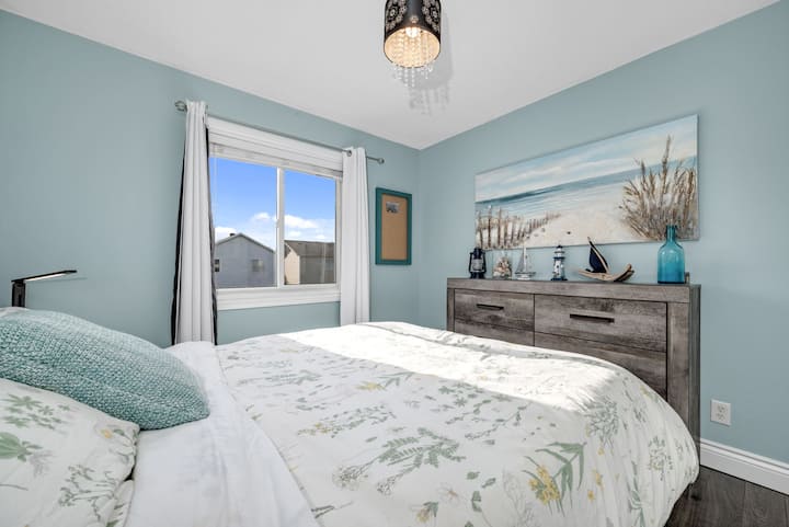 Sumérgete en un sueño junto al mar en este dormitorio tranquilo, con una acogedora cama tamaño queen, sábanas frescas y cortinas que oscurecen la habitación para un sueño perfecto durante la noche.