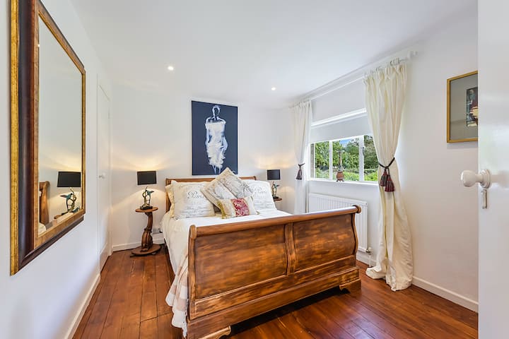 Dvojposteľ s kreslenou truhlicou a šatníkom.  Izba s výhľadom do záhrady.