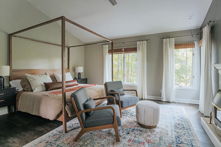 La chambre principale est magnifiquement aménagée avec un lit king size à baldaquin et un coin salon relaxant avec de belles vues boisées et une vue saisonnière sur l'un des étangs jumeaux adjacents.