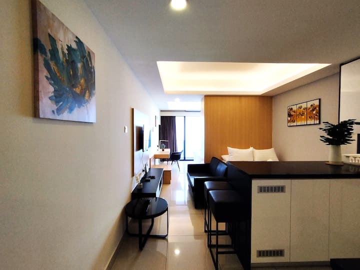 Მისაღები ოთახი 1 საწოლით, ტყავის დივნით და ტელევიზორითა და ტელევიზორის ყუთით.