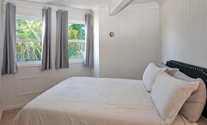 ห้องนอนใหญ่ชั้นล่างพร้อมเตียงควีนไซส์เครื่องปรับอากาศโต๊ะข้างเตียงโคมไฟ (เปิดใช้งานระบบสัมผัสและที่ชาร์จ USB) และตู้เสื้อผ้า