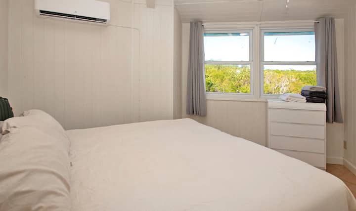 ห้องนอนใหญ่ชั้นบนพร้อมเตียงขนาดคิงไซส์เครื่องปรับอากาศโต๊ะข้างเตียงโคมไฟ (เปิดใช้งานระบบสัมผัสและที่ชาร์จ USB) ตู้เสื้อผ้าและตู้ลิ้นชัก