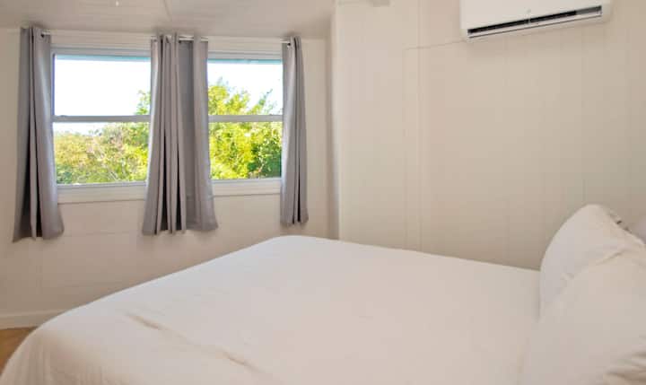 ห้องนอนชั้นบนที่สองพร้อมเตียงควีนไซส์เครื่องปรับอากาศโต๊ะข้างเตียงโคมไฟ (เปิดใช้งานระบบสัมผัสและที่ชาร์จ USB) และตู้เสื้อผ้า