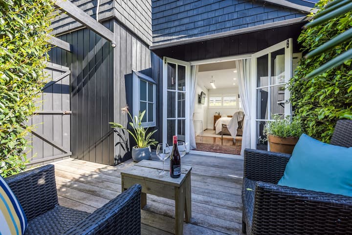 Cozy outdoor patio with wicker chairs, a small table with wine, and French doors leading to a bright interior room