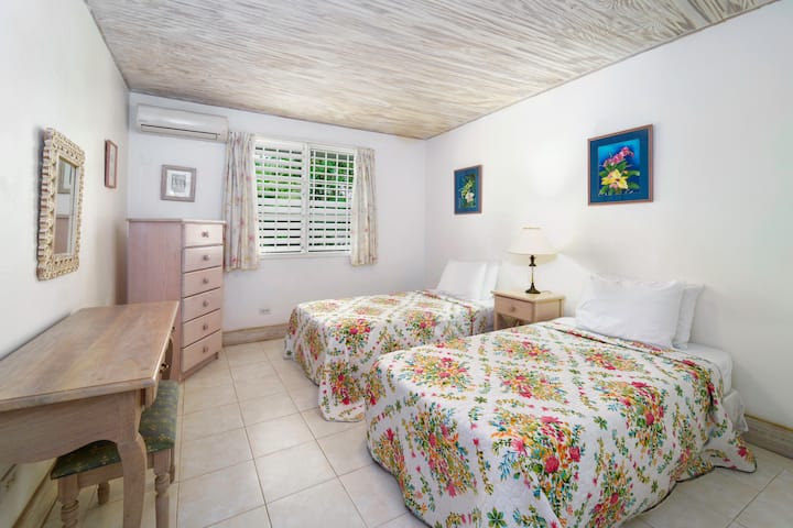 Guest bedroom with two single beds that can be made into a double Bed, Air Conditioning, clean linens, bedside lighting, dresser, desk 