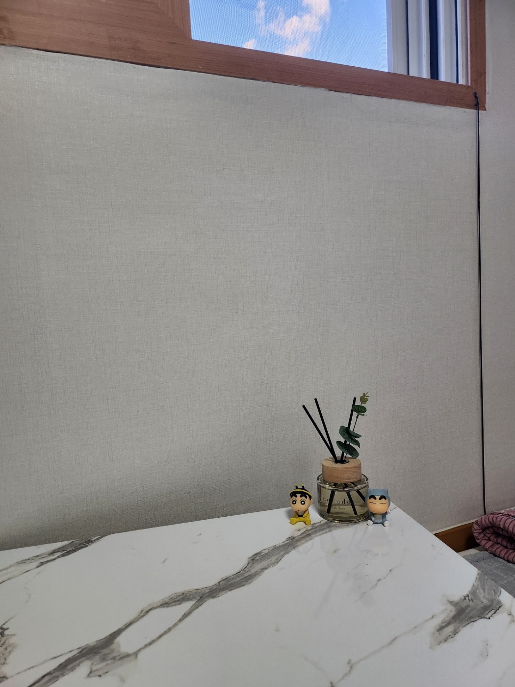 A marble tabletop is highlighted in this image, featuring a small potted plant and decorative figurines. Natural light streams in through a nearby window, illuminating the smooth texture of the tabletop and the soft colors of the decor.