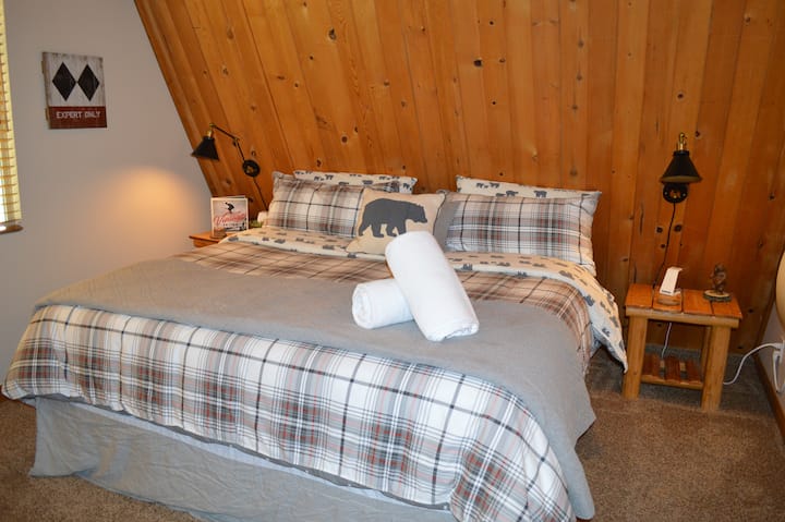 غرفة نوم رئيسية جميلة مع سرير مريح بحجم كينج مع نصف حمام ملحق، مزينة بموضوع التزلج، وشواحن آيفون، وسخان مخصص.