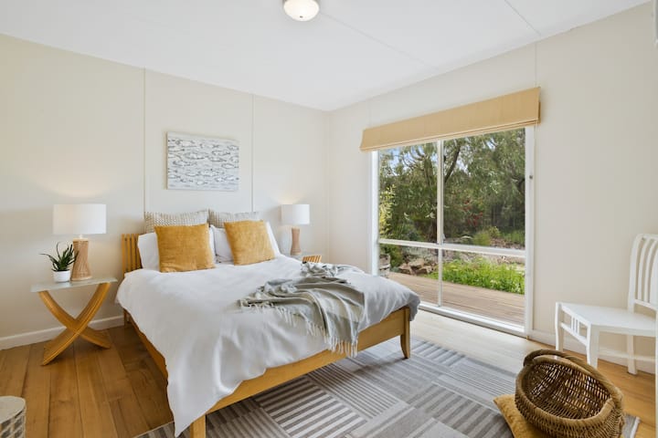 Cottage Main Bedroom | A sun filled bedroom with a Queen bed overlooking the beautiful native garden.