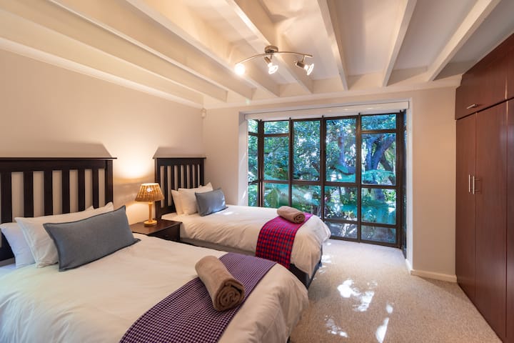 Bedroom 2 with 2 twin beds and ample cupboard space with amazing views of public gardens and Milkwood trees