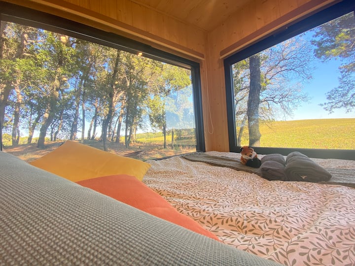 Le lit mesure 160x200 cm (queen size). Les baies vitrées immersives offrent une vue sur le vignoble. Des stores permettent de couper le jour