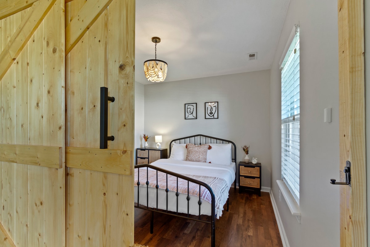 Charming Bedroom 2 with a queen-sized bed and unique barn-style sliding door, adding a rustic touch to this cozy space.