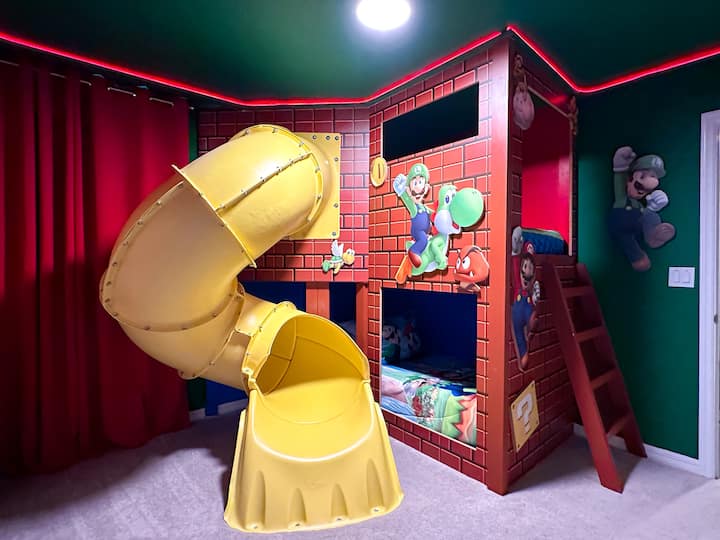 Tauche ein in ein Super-Mario-Abenteuer: ein individuelles Etagenbett mit Ziegelmuster und lebendigen Luigi- und Yoshi-Grafiken, eine gelbe Wendelrutsche für Warp-Pipe-Nervenkitzel und eine Regenbogen-LED-Deckenverkleidung. Ein weicher Teppich und prächtige rote Vorhänge umrahmen diesen verspielten Power-Up-Bereich.
