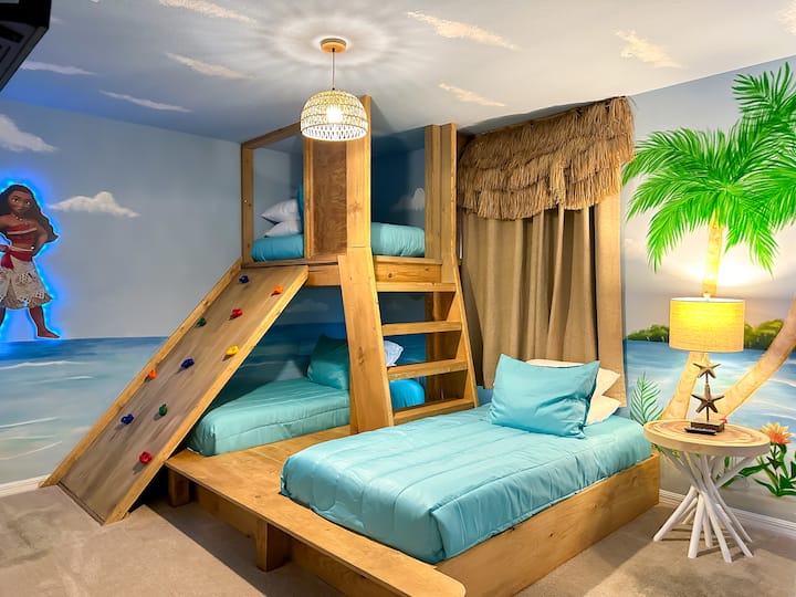 Setze die Segel zum Traumland mit diesem von Moana inspirierten Rückzugsort! Handgemalte Wandmalereien mit Meeresmotiven und von Palmen gesäumte Hüttenvorhänge umgeben eine individuelle hölzerne Etagenplattform mit einer Kletterleiter und weichen türkisfarbenen Matratzen. LED-Figurenkunst