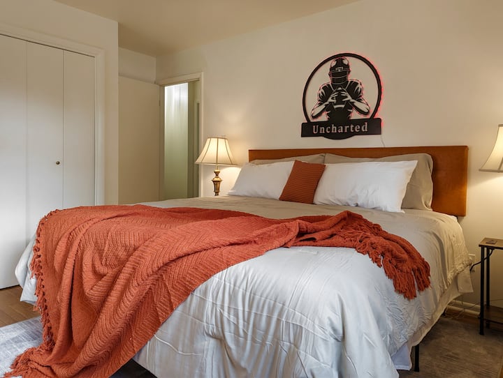 Narančasta spavaća soba ima madrac u veličini grada Dreamcloud.  Ima izravan pristup zajedničkoj kupaonici.  U ormaru se nalaze predmeti vezani za djecu, uključujući stolicu za hranjenje, ruksak i nekoliko igračaka.