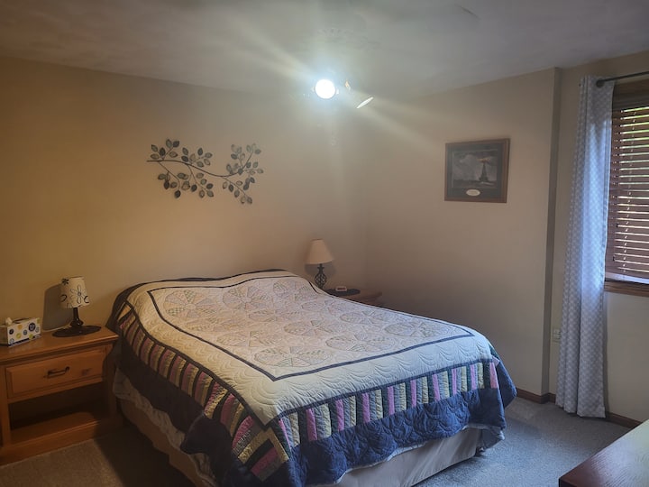 Bedroom with queen bed, closet, desk and nightstands.
