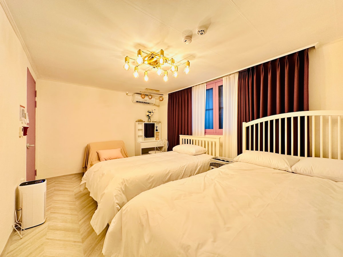 This is the big room at LAVENDER. There is one queen bed and one super single bed and one sofa bed.
The sofa bed can be added as an Xsra bed, so it can accommodate up to 4 people in this room if absolutely necessary. However, I think this room is the most ideal number of people staying for 3 people. Both the curtains and pillows of the bed are prepared with the same quality tea as the luxury hotel.  This room is also equipped with an air purifier, a dressing table, and a dryer and a hair straightener in the dressing table.