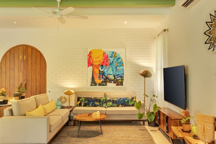 ✨A cozy corner where vibrant art meets earthy accents — this living room radiates warmth, with curated decor, soft lighting, and a pop of tropics under fresh green beams✨