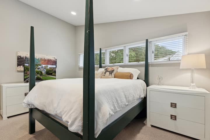 Chumba kikubwa cha kulala kilicho na kitanda cha malkia, kioo cha urefu kamili, dari za televisheni za skrini tambarare na kebo ya kifahari.