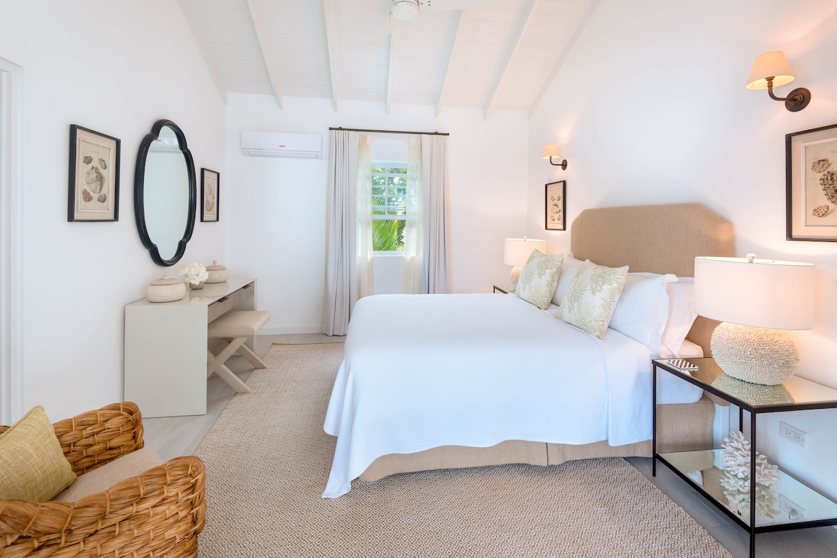 Un impresionante dormitorio tamaño queen en tonos neutros con mucho espacio para guardar ropa y un baño privado.  Esta habitación también cuenta con impresionantes vistas al mar.