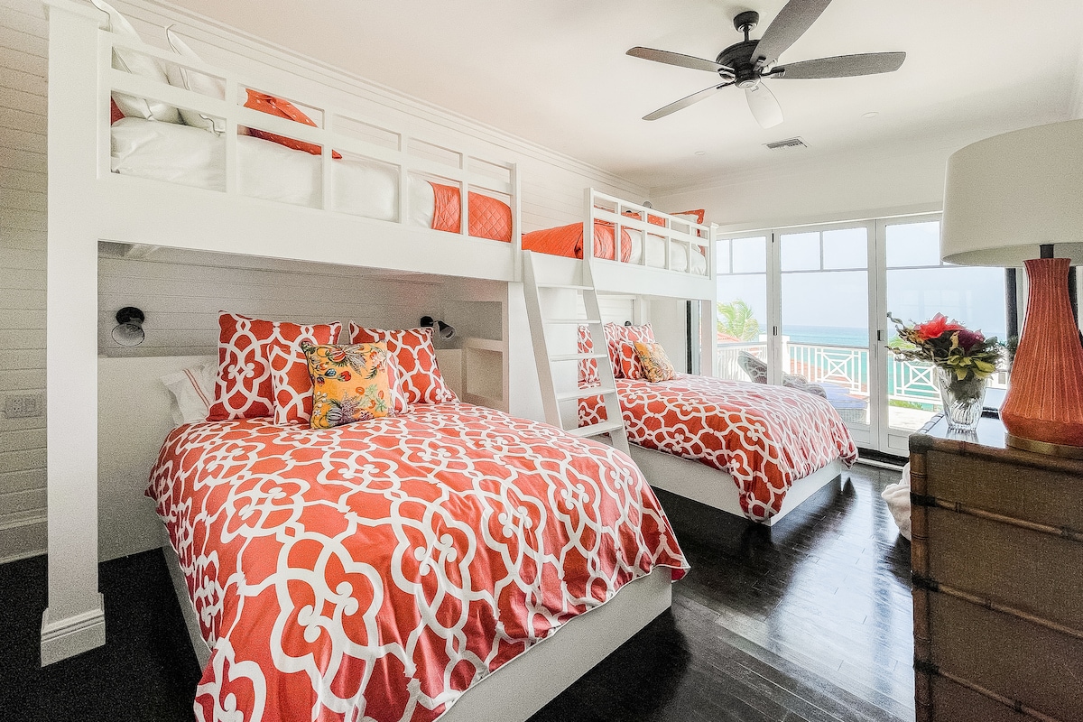 Dormitorio de la litera Coral en la planta superior. En la parte inferior 2 camas son Queens y las literas superiores son individuales. ¡Lleva al balcón del segundo piso con vistas a la piscina y al mar! Baño privado adjunto. 