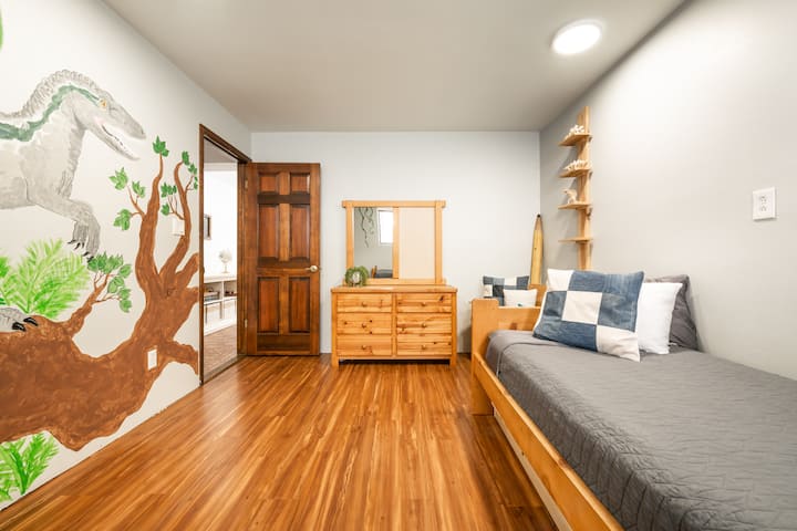 ห้องนอนชั้นล่างห้องที่สองยังมีเตียงแฝด 2 เตียงเตียงเตียงเดี่ยวที่มีขาติดล้อพื้นที่ตู้เสื้อผ้าและม้านั่งมากมายและจิตรกรรมฝาผนังไดโนเสาร์ที่ทาสีด้วยมือ