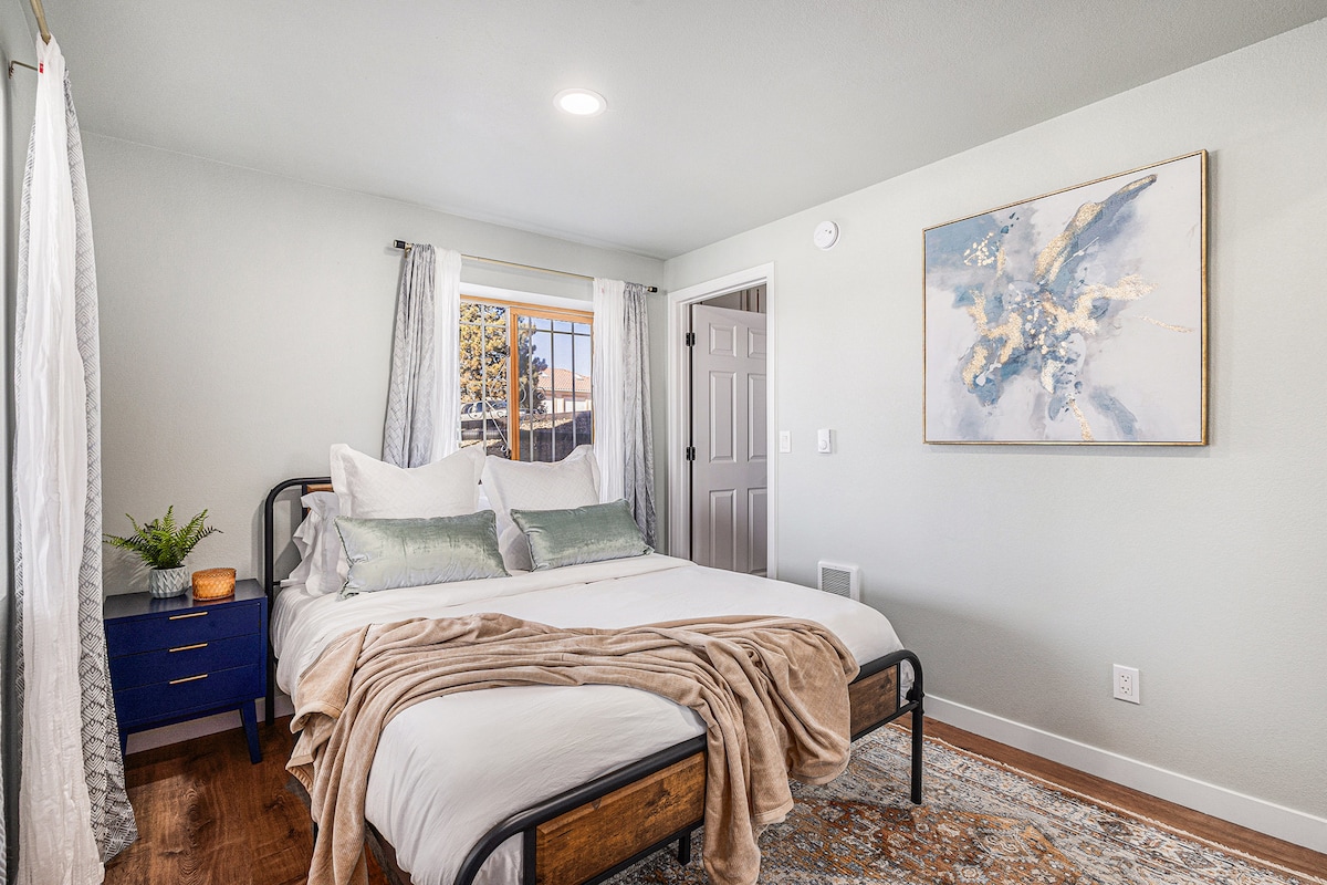 חדר שינה מואר ומאוורר לאורחים הכולל מצעים רכים, אור טבעי ונופים שלווים.