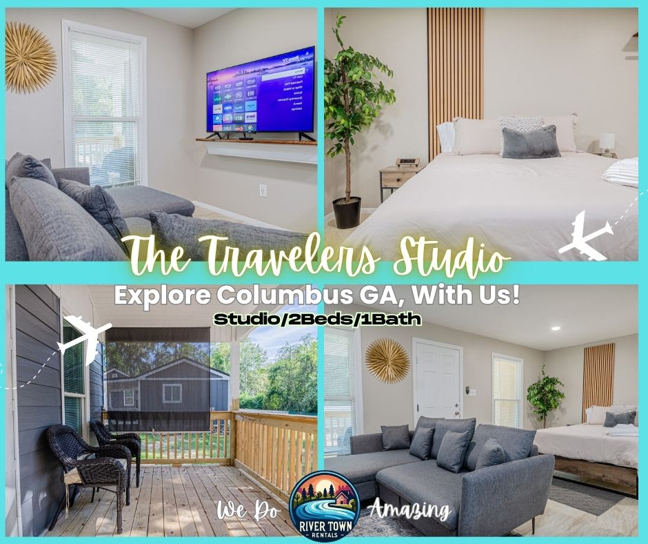 A cozy studio layout is captured, featuring a spacious bed dressed in neutral tones with a textured throw. A large TV is mounted on the wall above a simple shelf. The inviting seating area includes a comfortable gray sofa, all set against a backdrop of natural light from large windows.