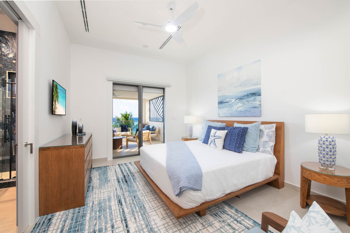 Quarto 6 com cama king size, TV HD e acesso à varanda com vista para o mar.