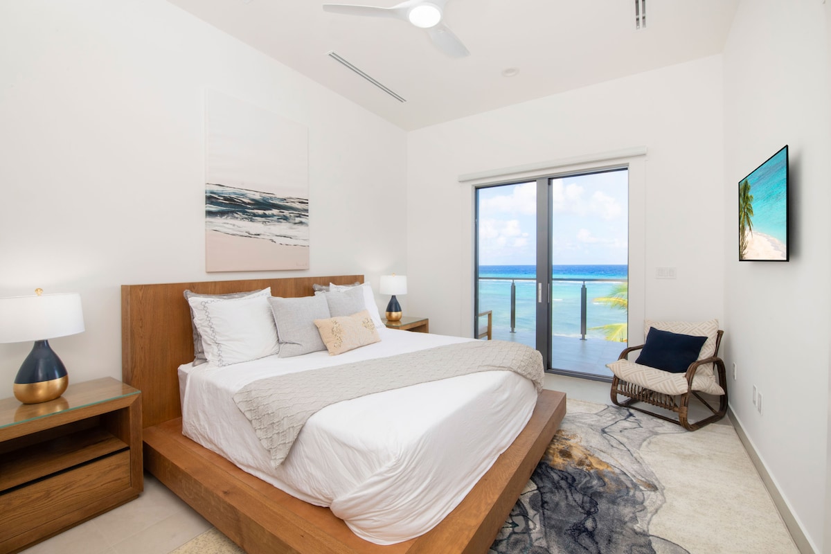 Quarto 4 com cama king, TV HD e acesso à varanda com vista para o mar.