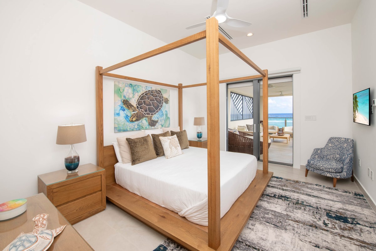 Quarto 3 com cama king size, TV HD e acesso à varanda partilhada com vista para o mar. 