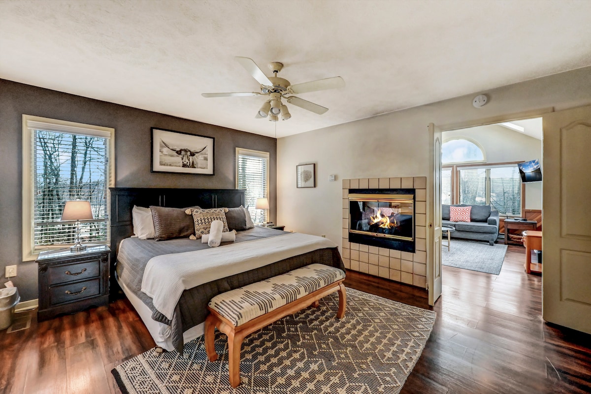 ห้องนอนบนชั้นหลักพร้อมเตียงคิงไซส์ที่ก่อกองไฟและห้องน้ำในตัว
