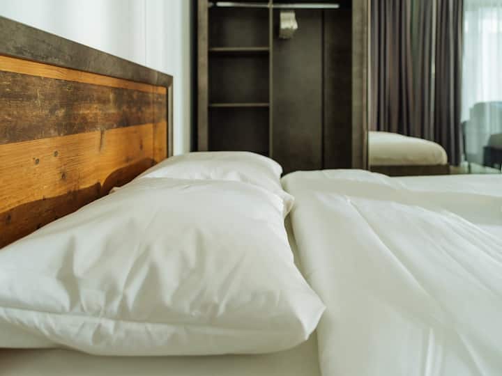  מצעים רכים וצוננים על מיטת קווין סייז מרווחת עם מסגרת עץ ואחסון מובנה. מושלם ללילות נינוחים אחרי סיור בעיר.