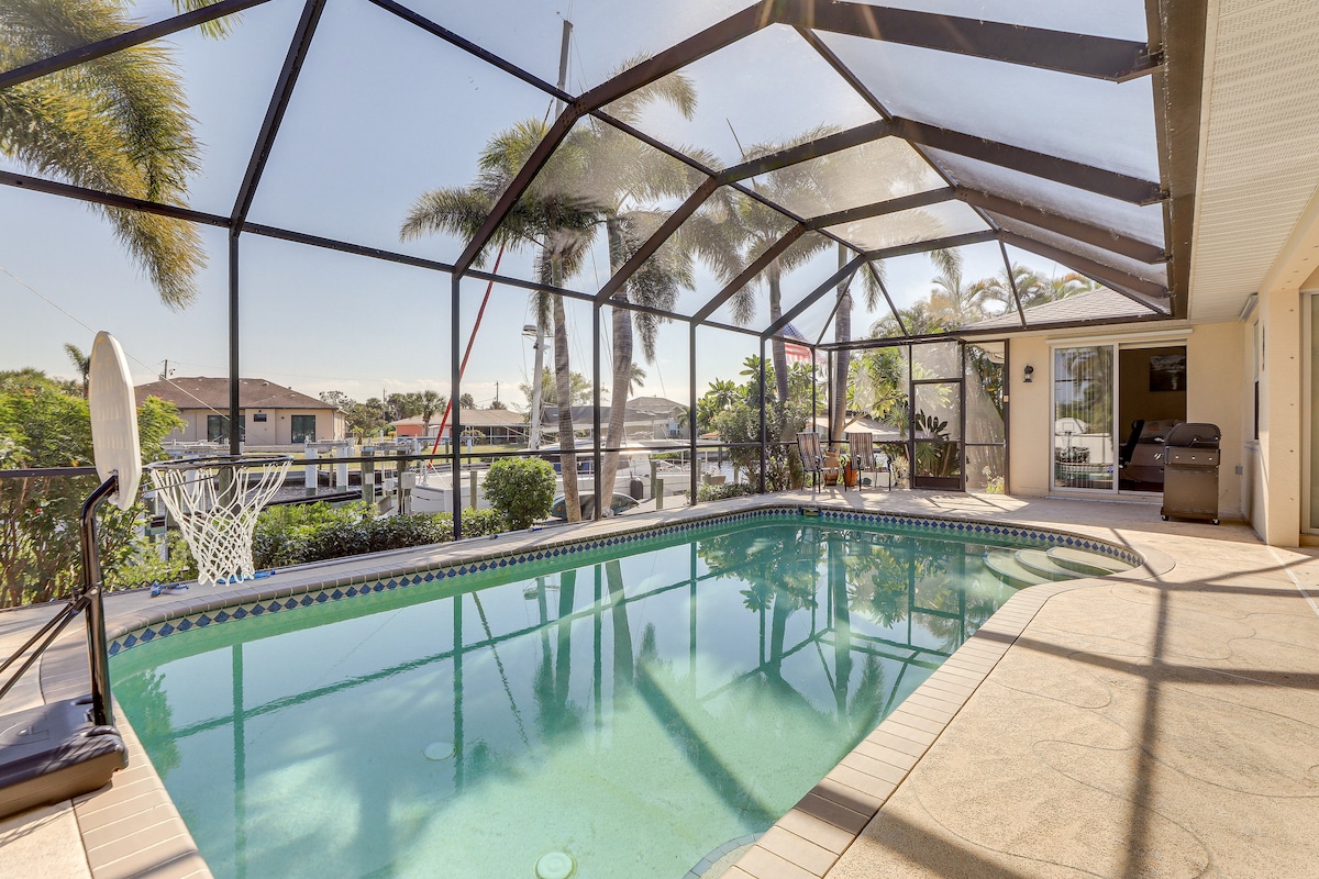 The screened outdoor area features a private pool surrounded by palm trees, allowing for views of the water. A basketball hoop is visible by the poolside, while lounge chairs provide seating options for relaxation.