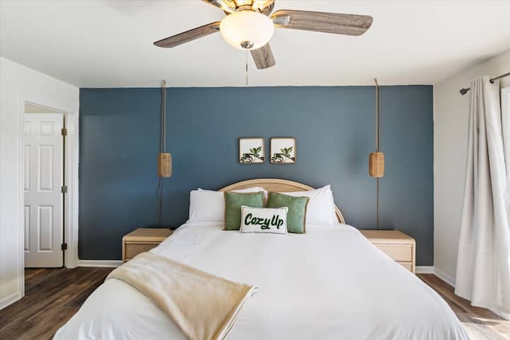 Un lit King Size est centré contre le mur bleu sarcelle de la chambre principale.