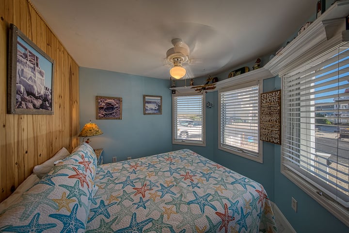 Č. 1 Izba Starfish s manželskou posteľou, výhľadom na duny, nočným stolíkom, nočnými stolíkmi s komodou, šatníkom, zrkadlom a stropným ventilátorom.  V tejto skrini sú detské stoličky k konferenčnému stolíku v obývačke a ďalekohľad pre vás.