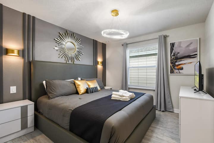 Quarto chique com cama king, toques dourados, iluminação moderna e tons de cinza luxuoso