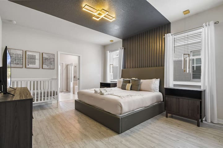 Suíte master moderna com cama king size, iluminação elegante, banheiro privativo e berço incluso