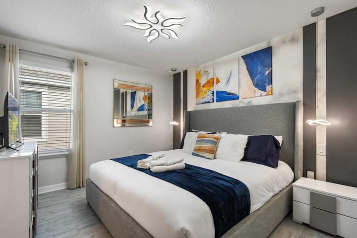Quarto contemporâneo com cama king, arte abstrata e iluminação única de designer