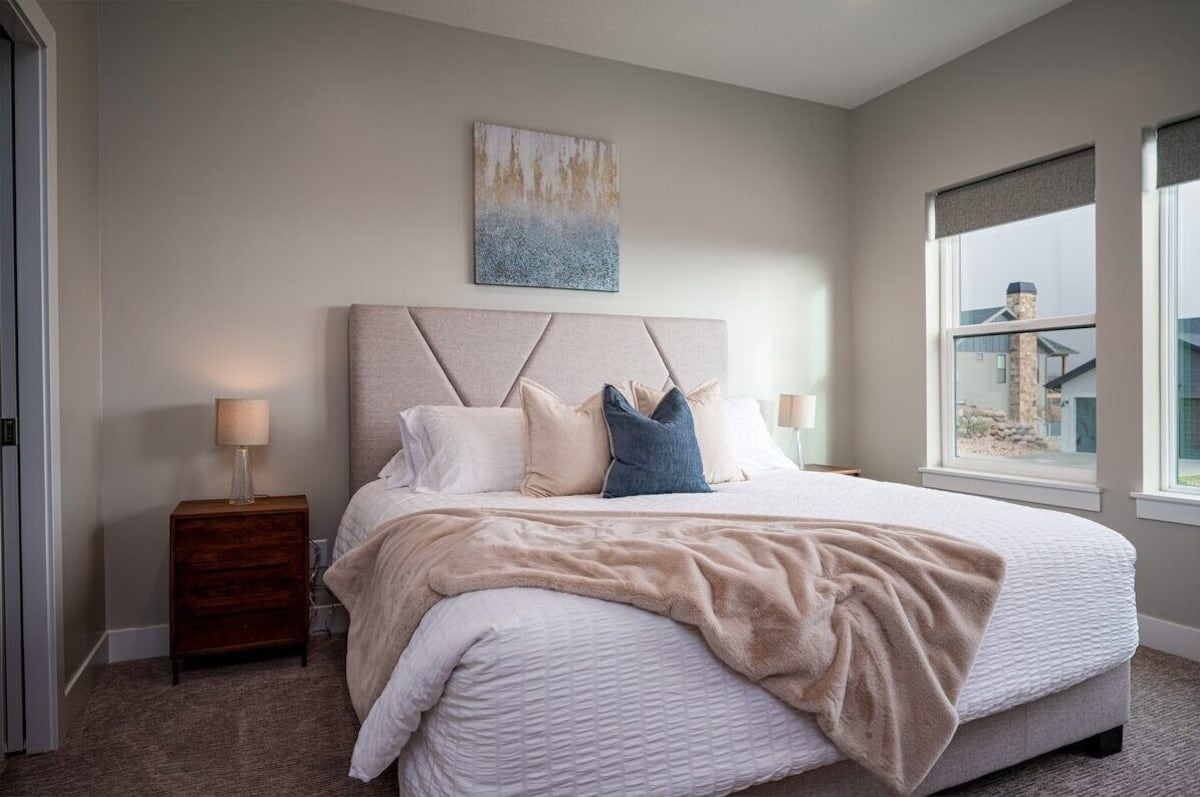 Chumba cha kulala cha msingi kina madirisha makubwa na kitanda cha ukubwa wa kifalme na mapambo ya kupendeza.