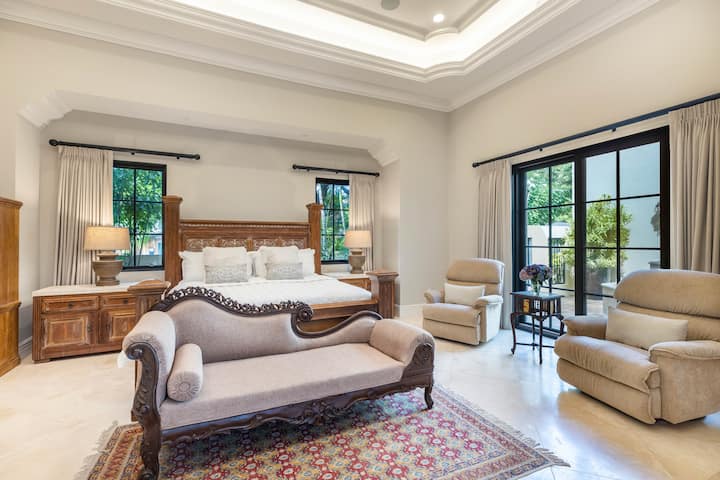 La lujosa suite principal cuenta con una cama tamaño king, techos elevados y acceso al lanai.