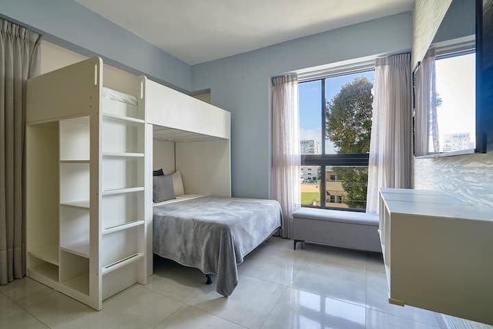 Táto izba je ideálna pre rodiny alebo skupiny a má poschodovú posteľ s manželskou posteľou v spodnej časti a oddelenou posteľou na vrchu. Užite si zábavu s inteligentným televízorom a dostatkom úložného priestoru v priestrannej skrini — útulnom a praktickom priestore pre všetkých!